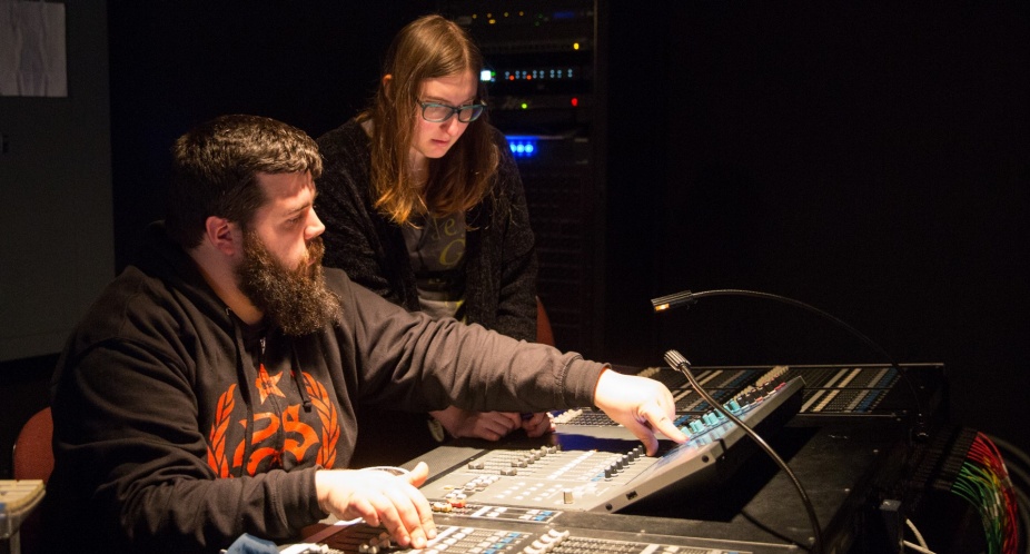 Two students working at a sound board. 