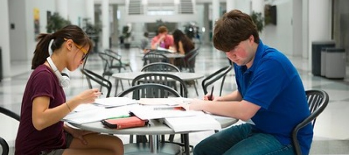 two students studying at a table in the UBCFA atrium. 