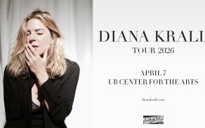 Diana Krall standing in front of a curtain with her hand on her chin and her eyes closed. 