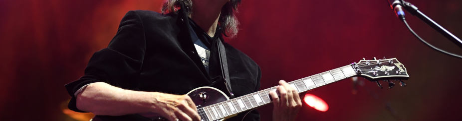 Steve Hackett playing guitar on stage with eyes closed head raised. 