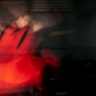 Blurred motion of a dancer in a flowing red costume. 