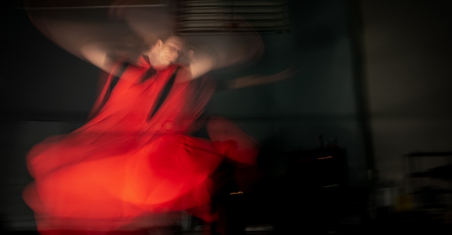 Blurred motion of a dancer in a flowing red costume. 