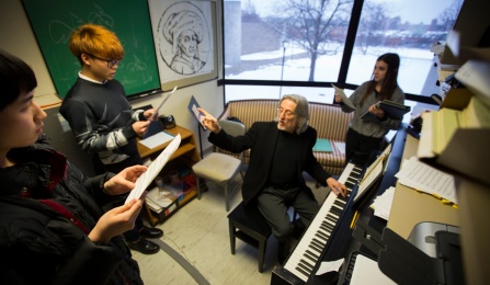 Students and a professor around a piano. 