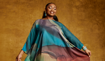 Samara Joy posing in a coloful flowing dress while smiling. 