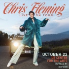 chris fleming posing in front of a car wearing a faux fur coat with mountains and trees in the background. 