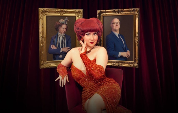 Lucy Darling sitting and posing in front of framed pictures and a velvet curtain.