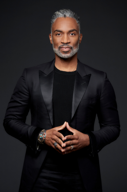 desmond posing with fingers touching wearing all black. 