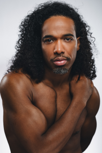 joe gonzalez posing without a shirt with arm across body. 