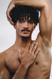 michael cherry posing without a shirt with one arm across body and one above head. 