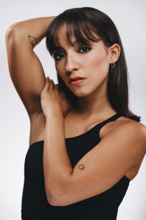 laura perich villasmil posing with one arm on shoulder and the other behind her head. 