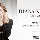 diana krall posing with eyes closed and hand over face in front of a curtain. 