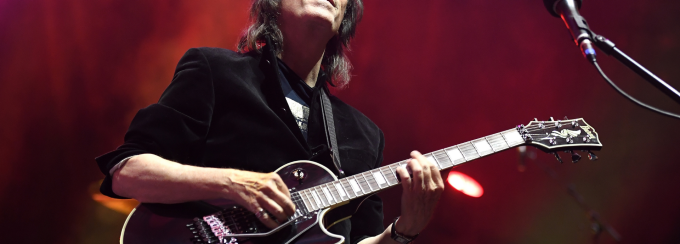 Steve Hackett playing guitar on stage with eyes closed head raised. 