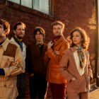 punch brothers standing in front of a brick building during sunset. 