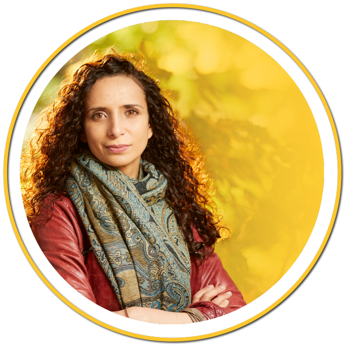 portait of Ella Al-Shamahi crossing her arms and wearing a scarf.