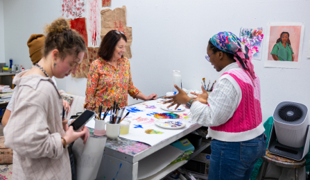 Student artist presenting their work on a table in their artist studio at Art in the Open.